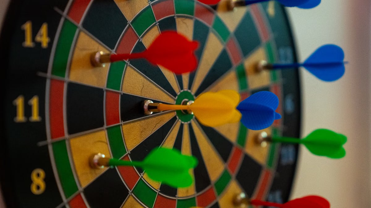 A close-up of vibrant colored darts on a dartboard, representing focus and precision in sports.